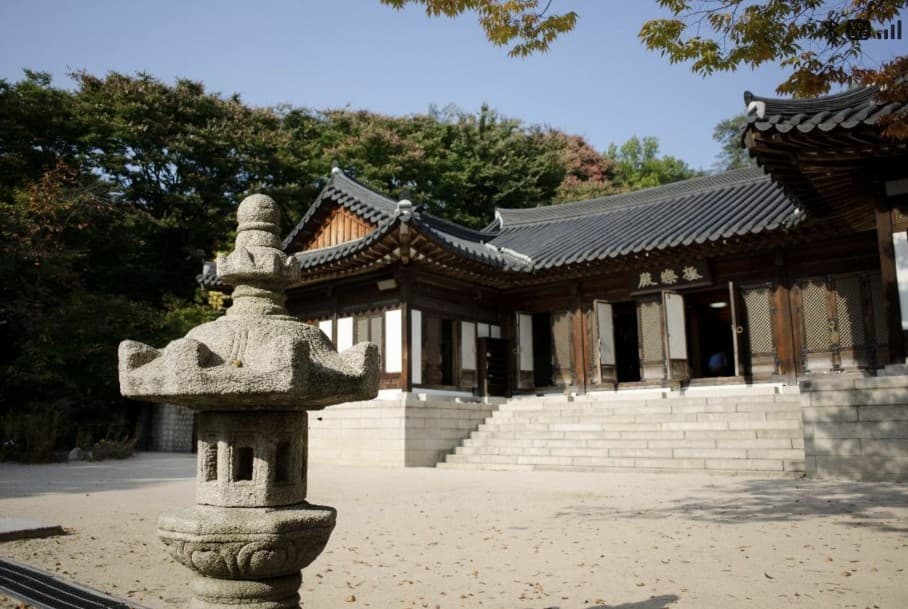 A stone lantern in the foreground with Gilsangsa's Geungnakjeon hall and sandy courtyard behind